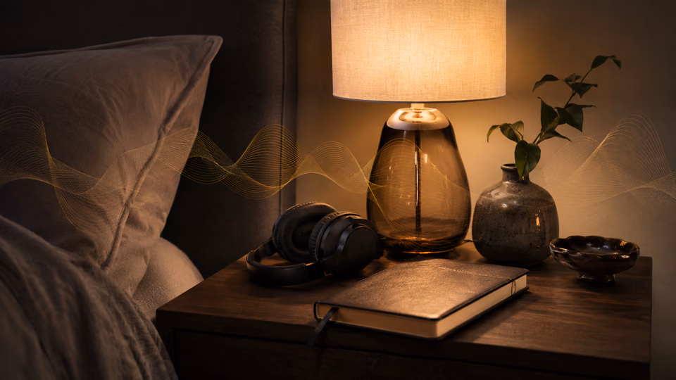 Warm bedside nightstand with journal, headphones, lamp, and calming sound waves